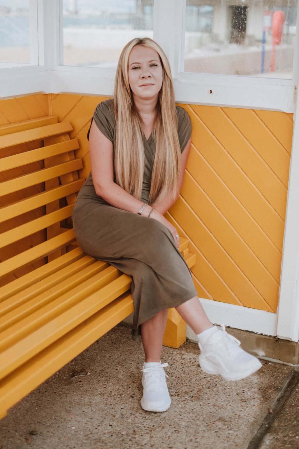Danielle Hunter sitting on a yellow bench in a seafront shelter